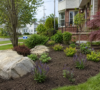 Premium residential landscaping services in Amherst NY featuring a custom interlocking paver patio, stone retaining wall, and native plant beds.