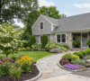 Front yard landscaping in Amherst featuring a flagstone walkway, stone retaining wall, flowering dogwood, and native flower beds.