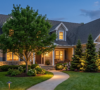 Illuminated walkway and stone facade of a modern Amherst home featuring warm 2700K low-voltage outdoor lighting at dusk.